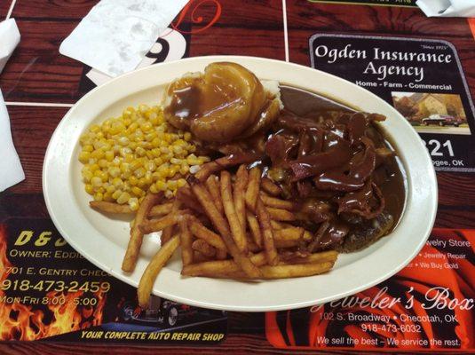 Hamburger steak with bacon and shredded cheese ontop with french fries, mashed potatoes, corn.