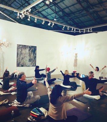 Meditators doing a yogic breath work exercise in preparation for meditation in the art gallery