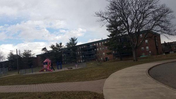 playground is in the shadows of four story apartment buildings