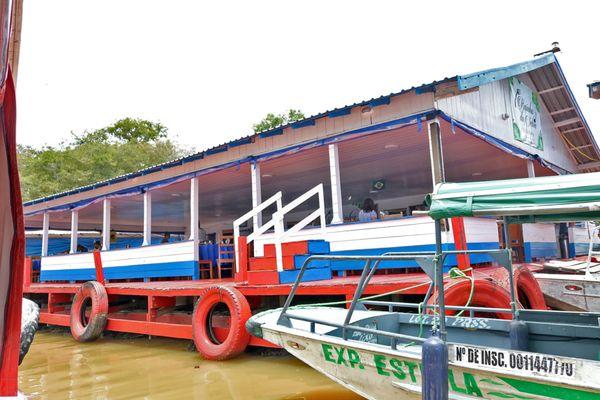 Tour boat tied up at the floating restaurant on a branch of the Amazon River