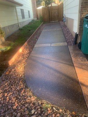 The sidewalk going from the side of the house to the backyard patio.