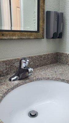 The wall mirror has a nice frame around it, not a builder grade design. Granite counter with a modern drop in sink.