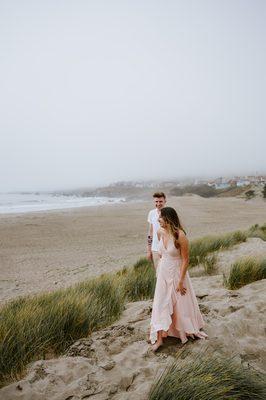 Couple walking along a dune at the beach hand in hand