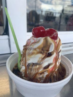 Caramel, peanut butter sundae with cherries on top.