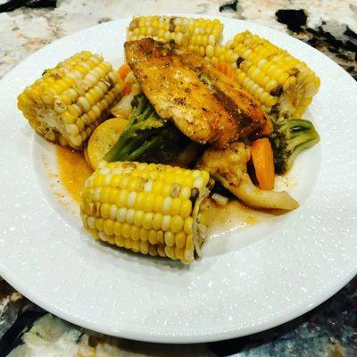 Pan seared salmon over steam vegetables and corn on the cob