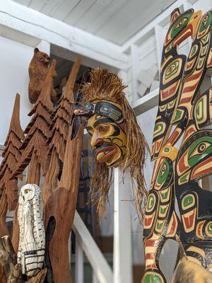 Upper arcade of gallery featuring First Nations art, carved trees, corner bear, and driftwood owl