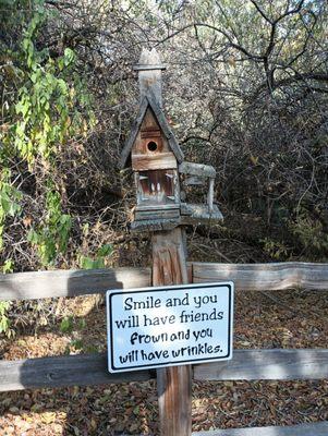 One of dozens of birdhouses with inspiring sayings.