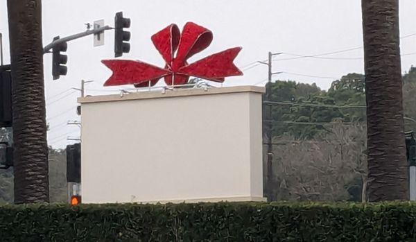 Christmas bow on top of the sign at the corner of the shopping center