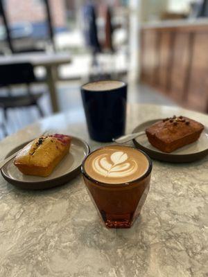 Chai latte in the back, passion fruit pound cake, and hazelnut caramel pound cake, and a cortado in the front.