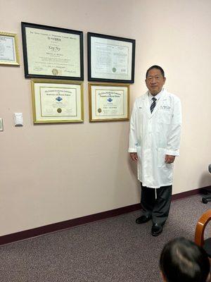 Dr. Xiang Fang in his office with his certifications