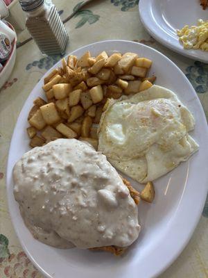 Chicken fried steak with gravy, home fries, and over easy eggs.