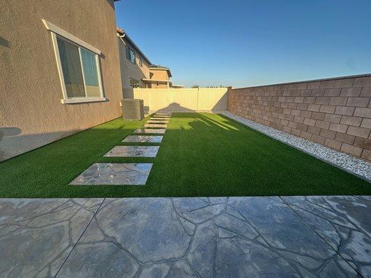 "Modern backyard with sleek stepping stones on vibrant turf, creating a clean and inviting outdoor space."