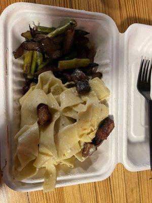 Homemade pappardelle pasta with carbonara sauce and bacon and a side of asparagus and red onion