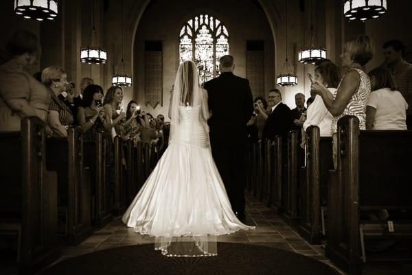 Bride and dad walk down aisle as groom looks on