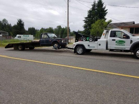 New age tow truck towing the early generation tow truck.