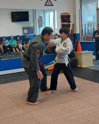 Younger student demonstrating a self-defense technique for his next level