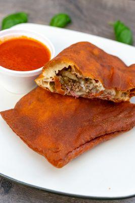 Combination calzone with a side of marinara sauce