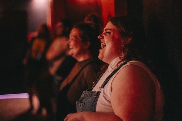 Some funny people watching other funny people up on stage.