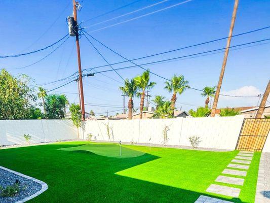 Back yard with hardscape design and freshly laid turf and putting green turf  by Crown & Blade Turf.