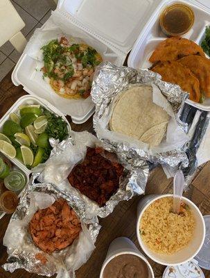 Shrimp tostada, birria queso tacos, beef & chicken fajita meat, corn tortillas, rice & beans, cilantro, limes, onions, & salsas.