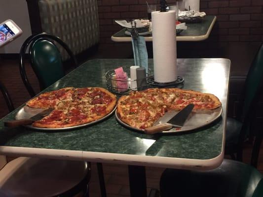 Two 14 inch pizzas, one with sausage and peppers, the other one with pepperoni and mushrooms.