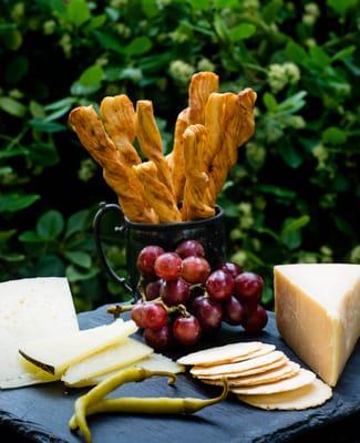 A Jam cheese plate with Manchego cheese, cheese sticks, Matiz Piparras with thins and grapes.