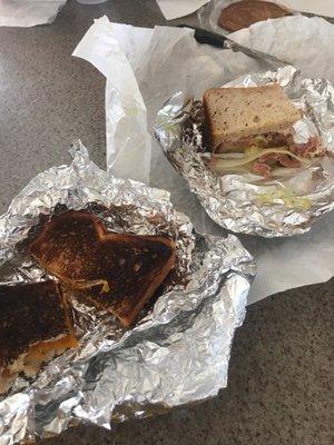 Delicious pastrami sandwich and terribly burnt grilled cheese.