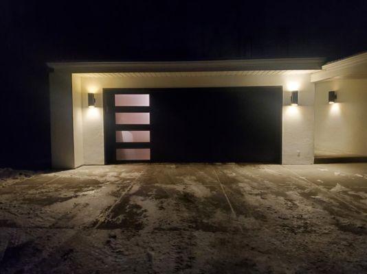 A photo of a black color, Flush Garage Door with rectangular windows.