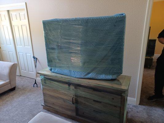 TV protected with heavy quilted blanket and plastic wrap