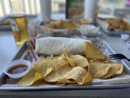 Carnitas burrito with chips and sauce.