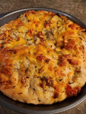 Homemade foccocia bread with artichoke, tomato, and cheese.