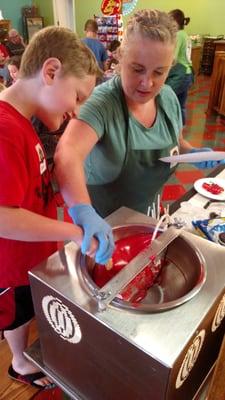 Coating a monster rice krispie bar in red chocolate