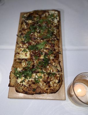 Alsatian flatbread that has chèvre, caramelized onion, and lardon