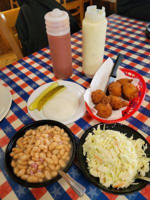 Hush puppies, cole slaw, baked beans, pickles, and raw onions