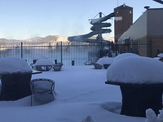 Inside, looking out through all the snow at the warm and inviting pool and slide.