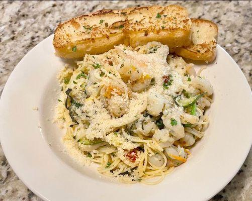 Pasta Primavera over angel hair with grilled shrimp, Parmesan, and a side of toasted garlic bread.