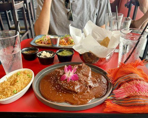 Chicken mole with side of tortillas and rice. Sweet potato tacos in background.