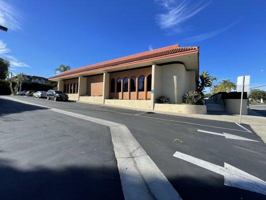 Front of building faces east with entrance to pkg lot on right into bank lot.