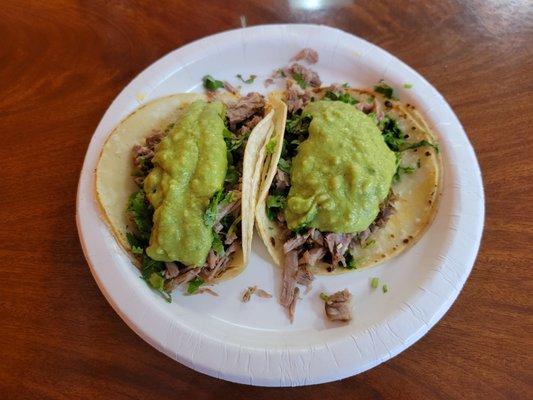 Tacos filled with Carnitas, and topped with Guacamole