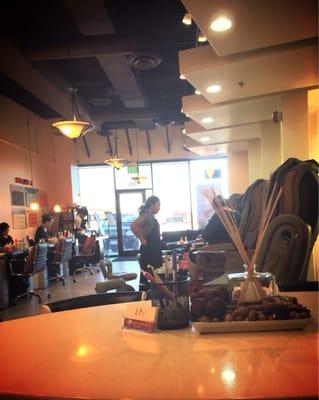 Sitting at drying table in back. Pedicure chairs on right side, nail tables on left.