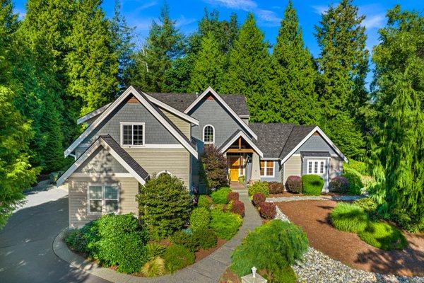 An inviting residential home showcasing a modern asphalt shingle roof, complemented by a mix of gray siding and decorative shingles.