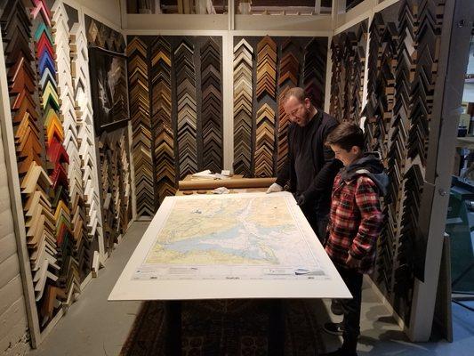 Jeff helping a son pick out framing materials for a map which is a gift to his father at the design counter.