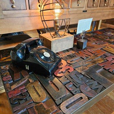 Letterpress type coffee table, vintage telephone and JennyK catcher's mask accent lamp.