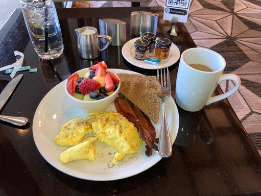 Scrambled eggs, bacon, toast and fruit