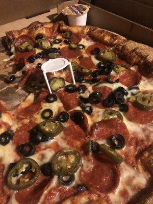 Pepperoni pizza with black olives and jalapeños