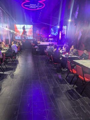 Restaurant interior showing the bar, a tv, tables, and patrons.