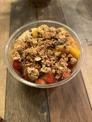 Half and half açaí and coconut bowl with GF granola, bee pollen, cacao nibs, strawberries, banana, and mango.