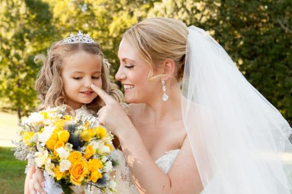 Photo of a beautiful bride playing with her flowergirl at her wedding.