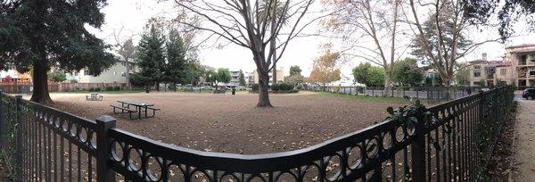 Fenced area trees, benches, grass patches, and picnic tables