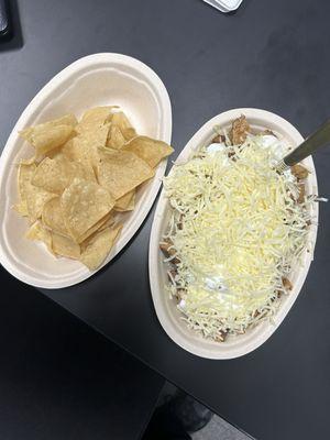 Burrito bowl with steak, chicken, white rice, black beans, hot sauce, sour cream, and cheese. Chips added for a "nachos" effect.